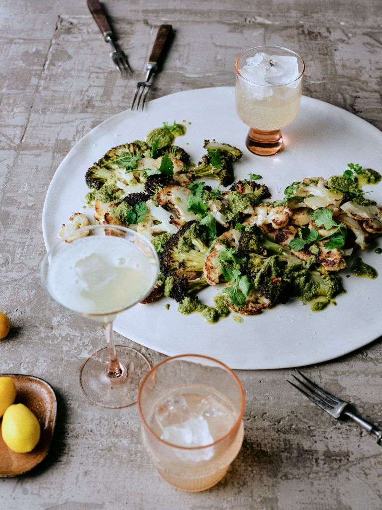 Gegrillter Blumenkohl und Brokkoli mit Kräuterpesto auf Teller mit Getränk - Rezept der Ausgabe querbeet vom Foodmagazin taste appeal–