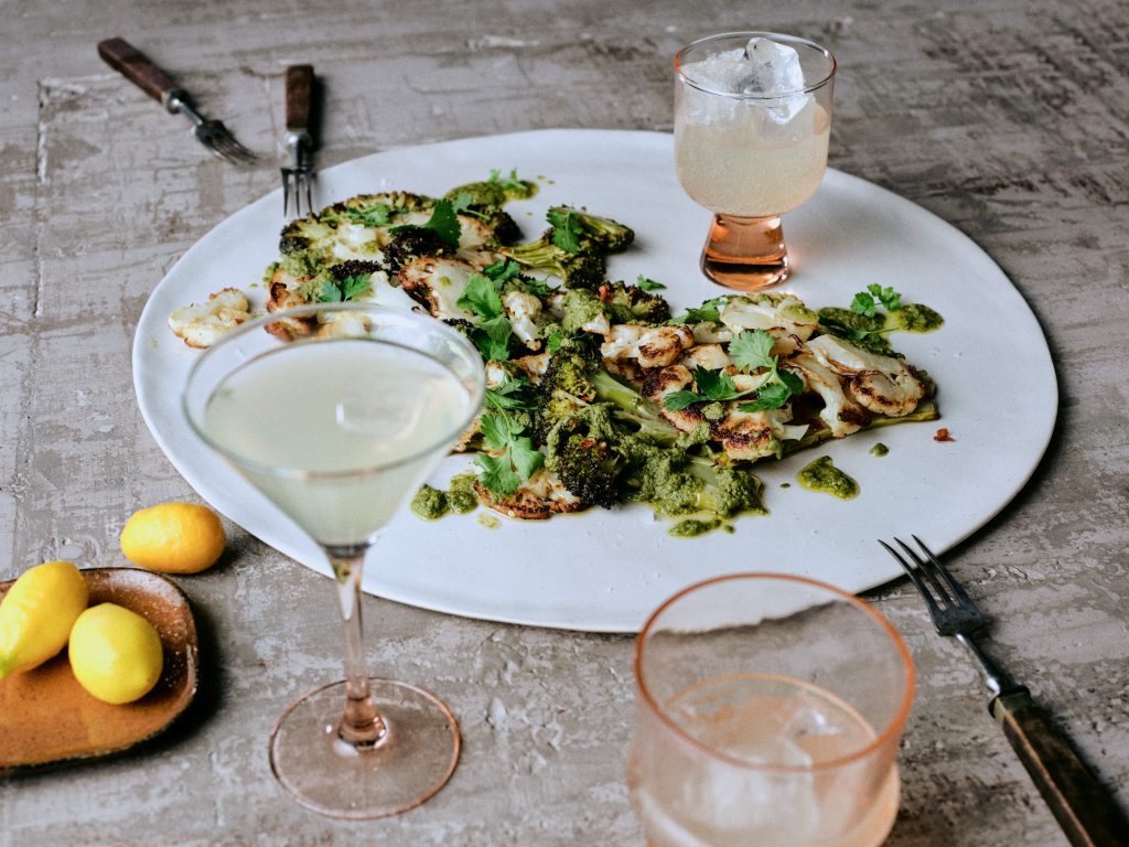Gegrillter Blumenkohl und Brokkoli mit Kräuterpesto auf Teller mit Getränk - Rezept der Ausgabe querbeet vom Foodmagazin taste appeal–