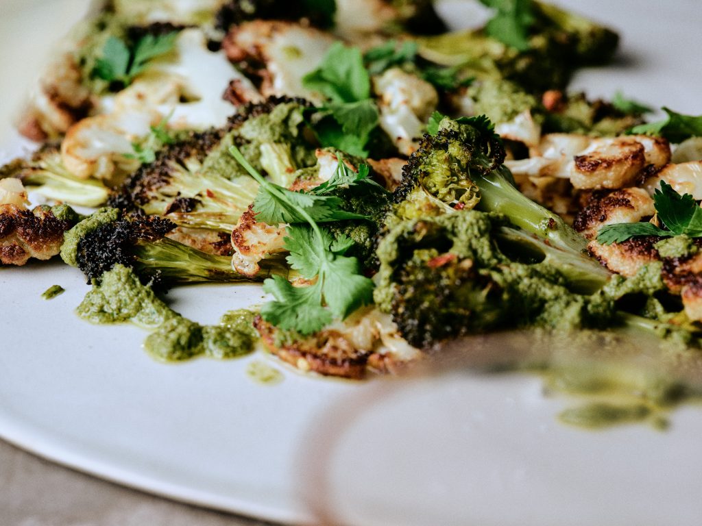 Gegrillter Blumenkohl und Brokkoli mit Kräuterpesto auf Teller - Rezept der Ausgabe querbeet vom Foodmagazin taste appeal–