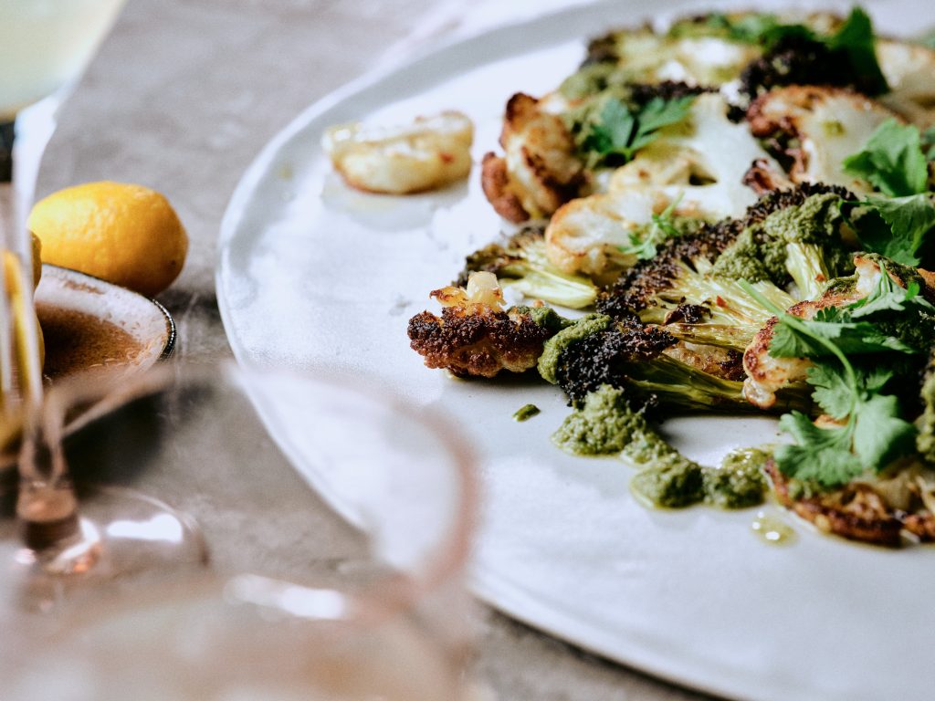 Gegrillter Blumenkohl und Brokkoli mit Kräuterpesto auf Teller - Rezept der Ausgabe querbeet vom Foodmagazin taste appeal–