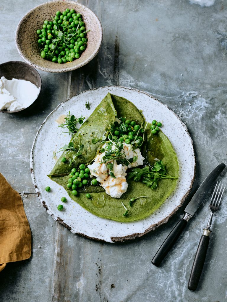 Foto von Spinat-Crepes mit Ziegenquark und Erbsen-Salat mit einer Schale Erbsen daneben - vegetarisches Rezeptfoto der querbeet Ausgabe von taste appeal– dem Foodmagazin