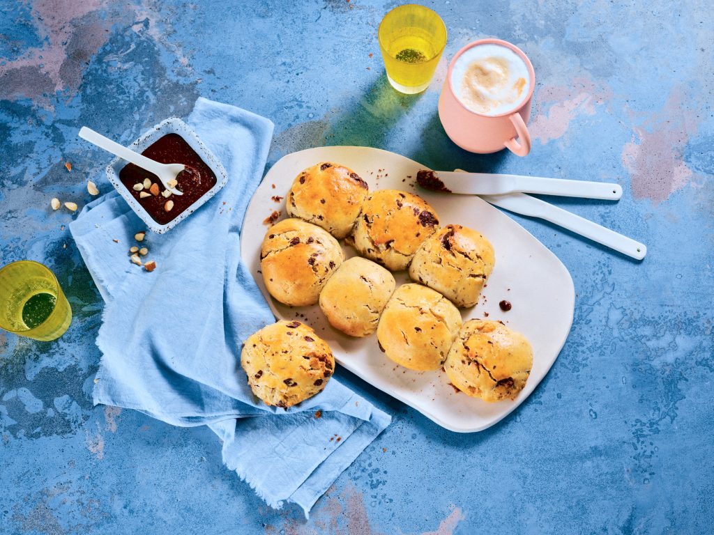 Totale, Vogelperspektive von TASTE APPEAL– Rezept: Schoko-Quarkbrötchen mit Schokonussaufstrich, daneben Besteck, gelbe Gläser und pinke Tasse