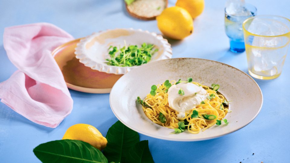 Totale von TASTE APPEAL– Rezept: Pasta mit Zitrone, Spargel und Burrata, im Hintergrund kleiner Teller mit Kresse, im Vordergrund Zitrone mit Blätter