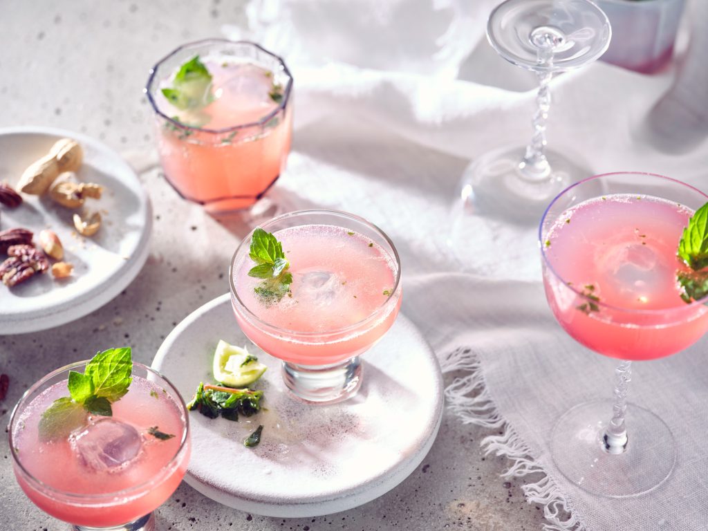 Totale von TASTE APPEAL– Rezept Kielliebe Drink mit Minze auf hellem Steinteller, mehrere Gläser nebeneinander