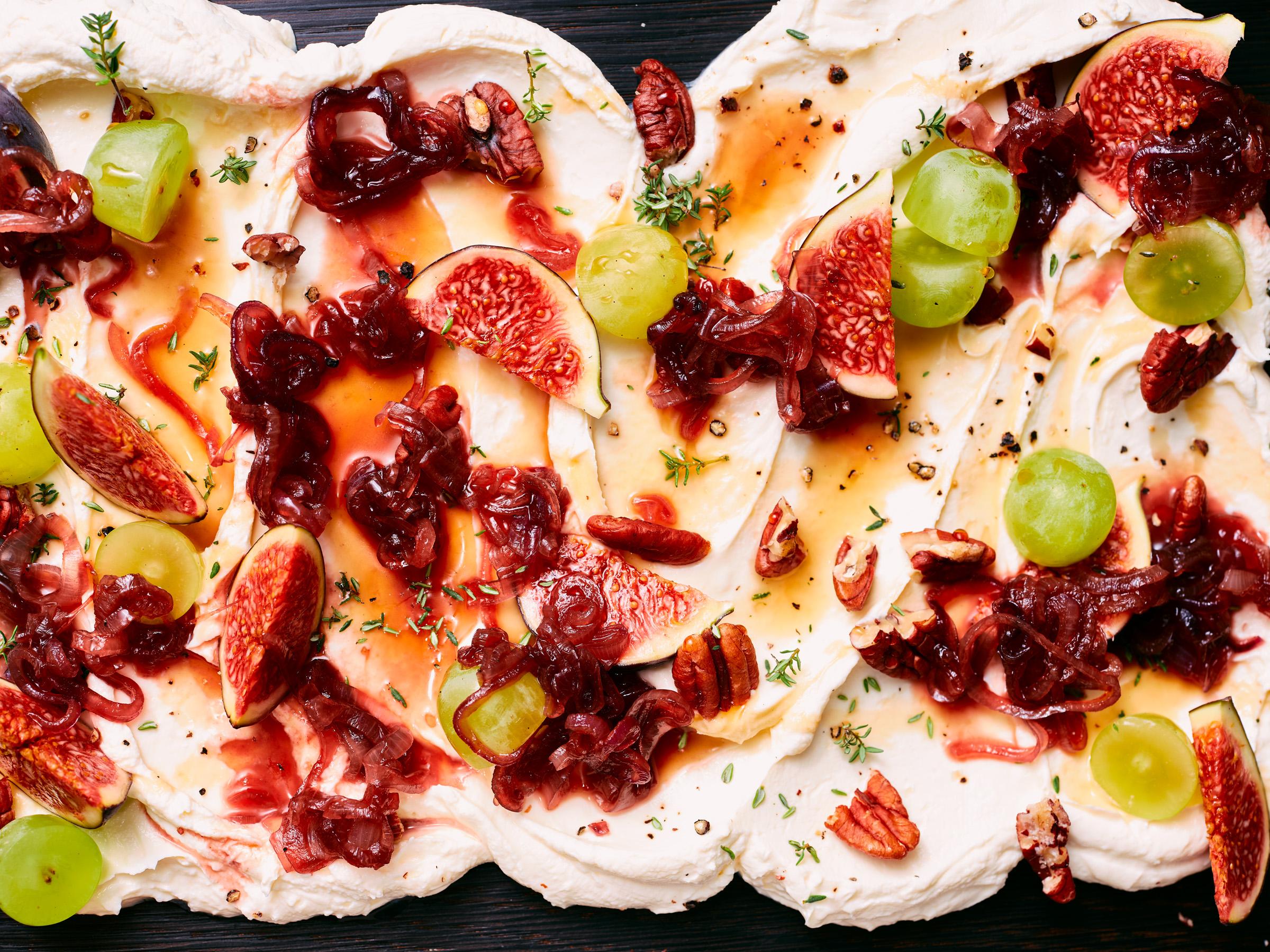 Detailaufnahme von TASTE APPEAL– Rezept Cream Cheese Board mit Nüssen, Feigen, Trauben & Thymian auf Holzbrett, Aufsicht