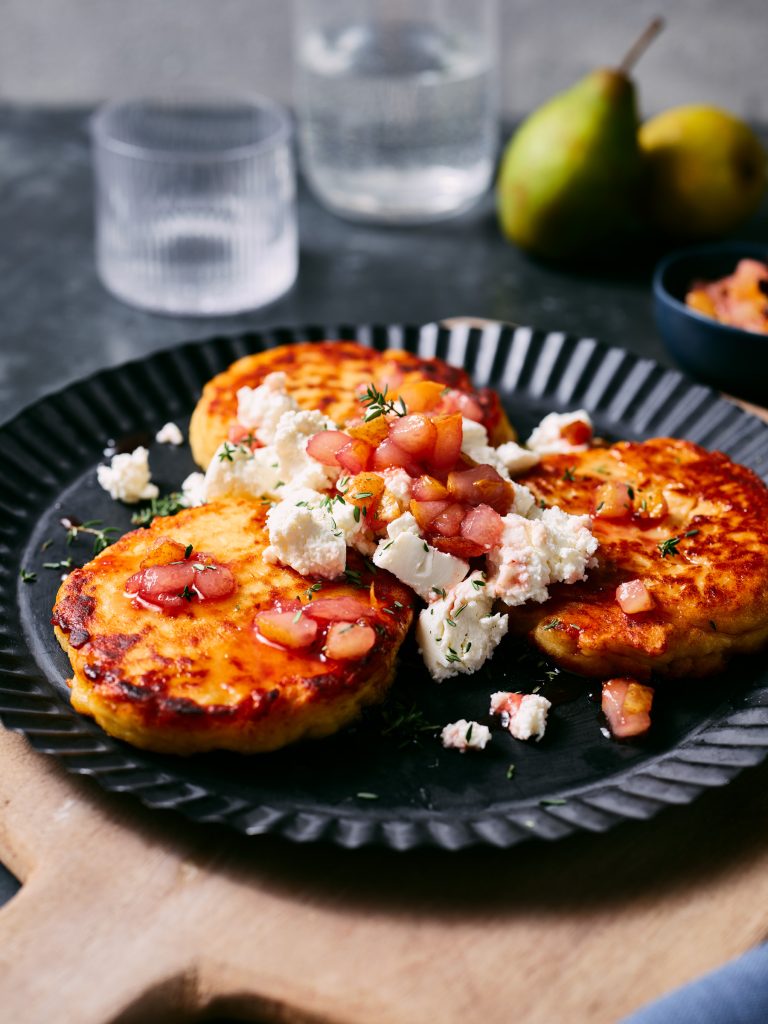 Nahaufnahme von TASTE APPEAL– Rezept Kartoffel Küchlein mit Ziegenfrischkäse und Birne auf schwarz Teller