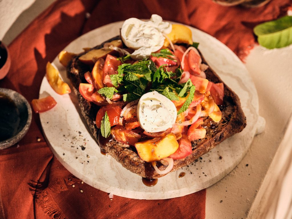 Totale von TASTE APPEAL– Rezept Tomaten-Brotsalat mit Pfirsich und Burrata auf Steinboden mit Tuch