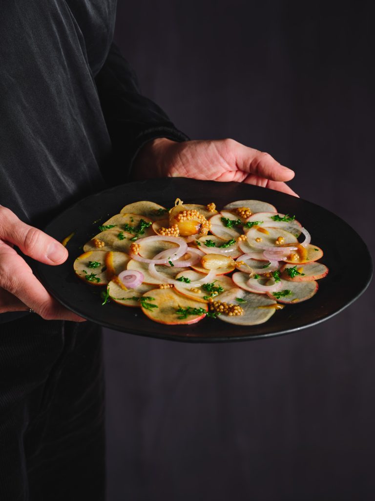 TASTE APPEAL- Rezept Apfel Carpaccio, mit fermentiertem Knoblauch und Senf, Hände halten Teller