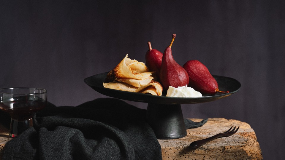 TASTE APPEAL- Rezept, Buchweizen-Pfannkuchen mit Rotweinbirnen in schwarzem, tiefen Teller, daneben dunkle Tischdecke