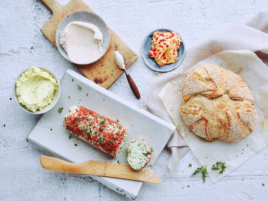 Totale von TASTE APPEAL– Rezept "Butter", vier verschiedene Butter auf hellem Steinuntergrund mit Brot