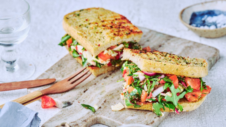 Nahaufnahme von TASTE APPEAL– Rezept: Chop Chop Sandwich auf Steinbrett, daneben Holzbesteck