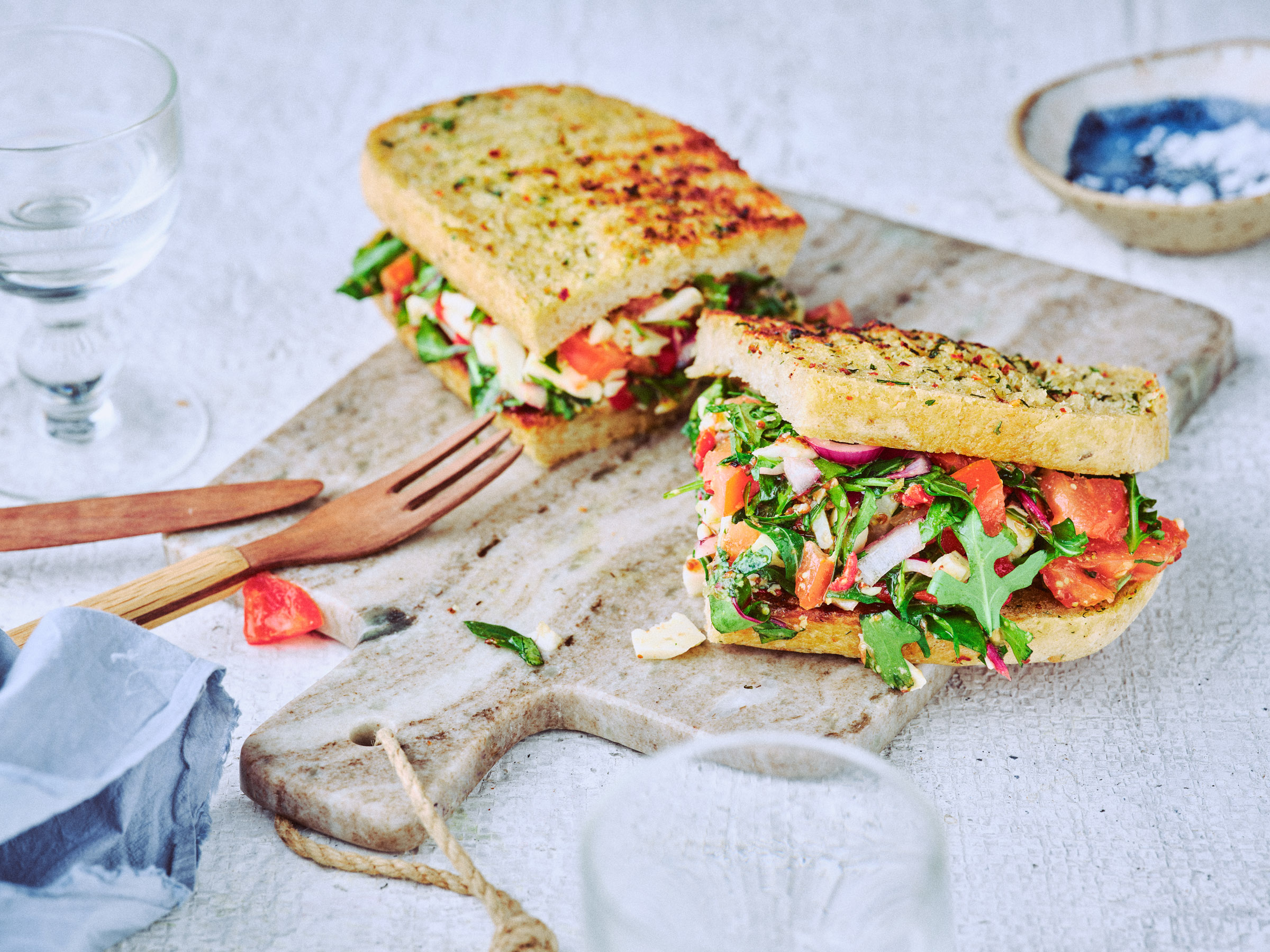 Nahaufnahme von TASTE APPEAL– Rezept: Chop Chop Sandwich auf Steinbrett, daneben Holzbesteck