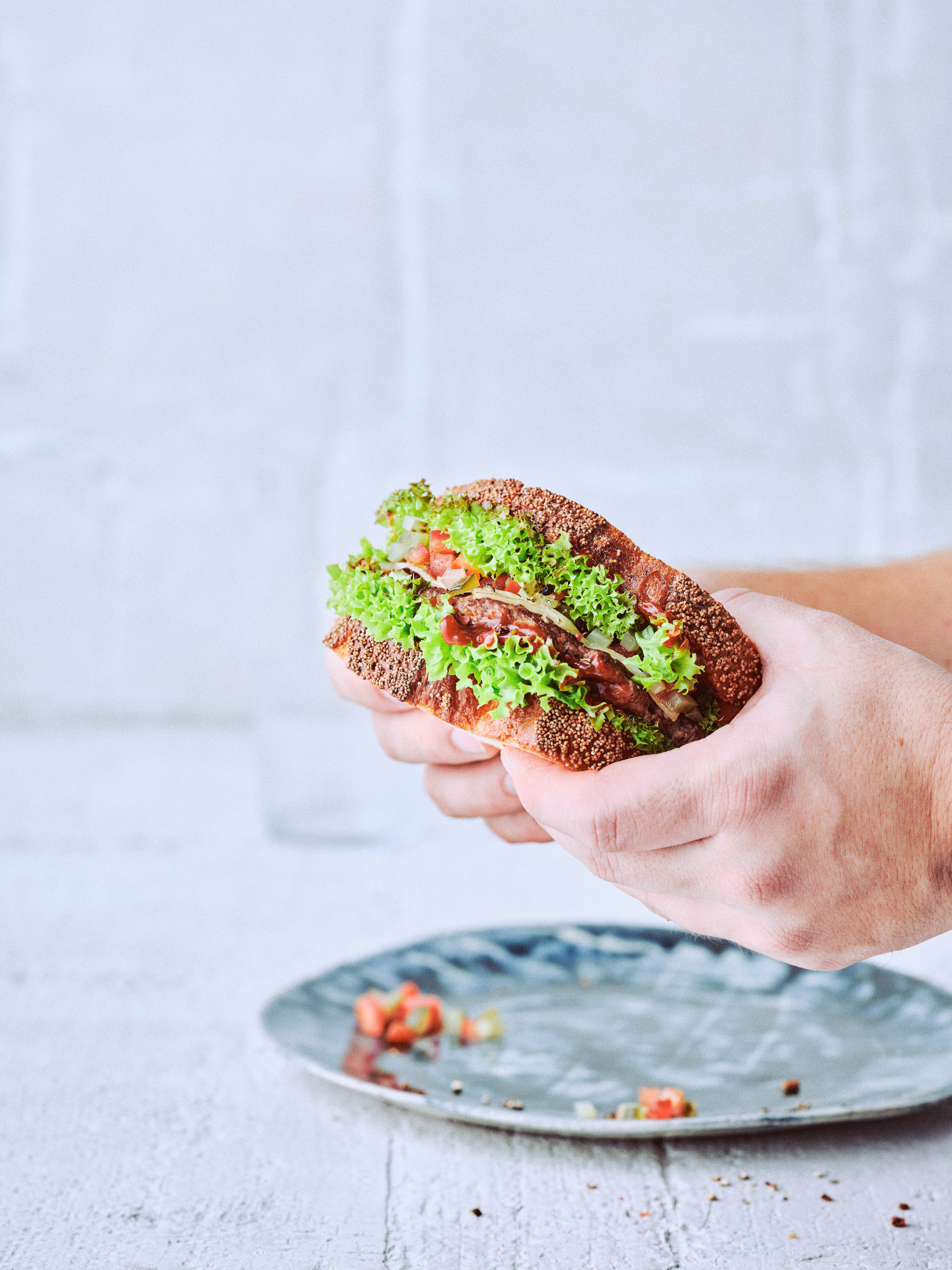 Männerhände halten Smash-Sandwich hoch, Rezept von TASTE APPEAL– aus der KNUSt-Ausgabe